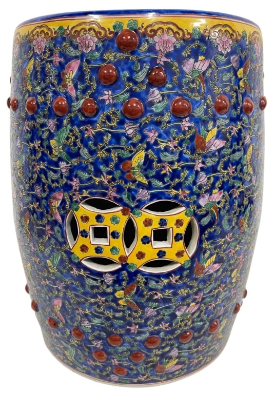 CHINESE FAMILLE NOIRE GARDEN STOOL 16": Chinese porcelain garden stool featuring a cobalt blue ground decorated with colorful scrolling floral vines, butterflies, and foliate motifs. The cylindrical form is accented with raised stud details