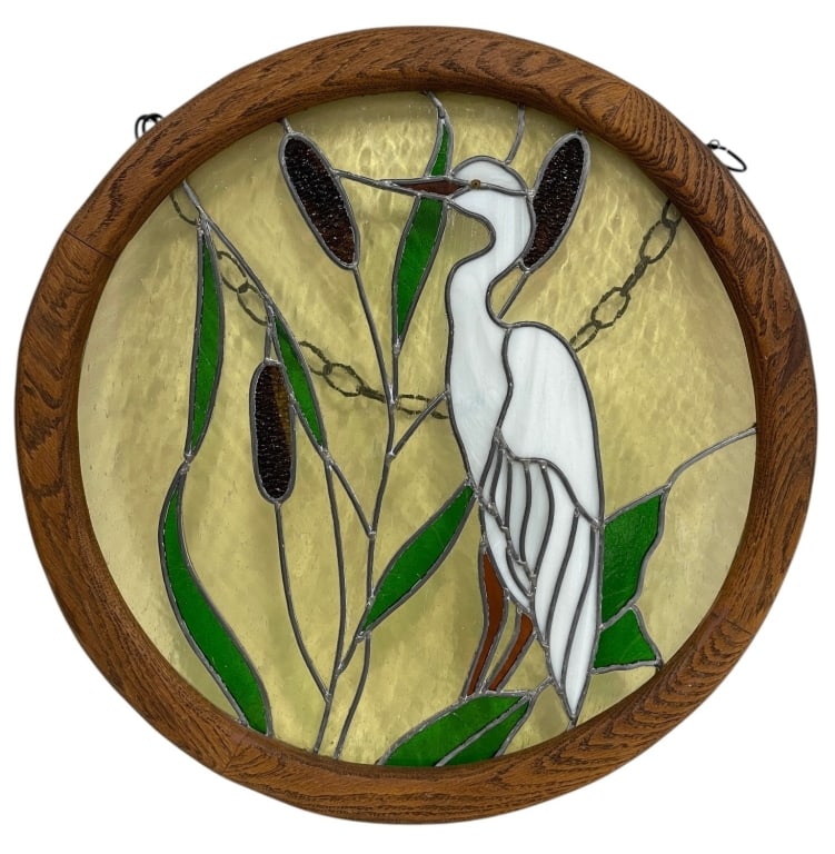 STAINED GLASS EGRET WINDOW PANEL 24in: Circular stained glass window panel depicting a white egret standing among cattails and marsh foliage. The design incorporates textured and opalescent glass in shades of white, green, amber, and brown