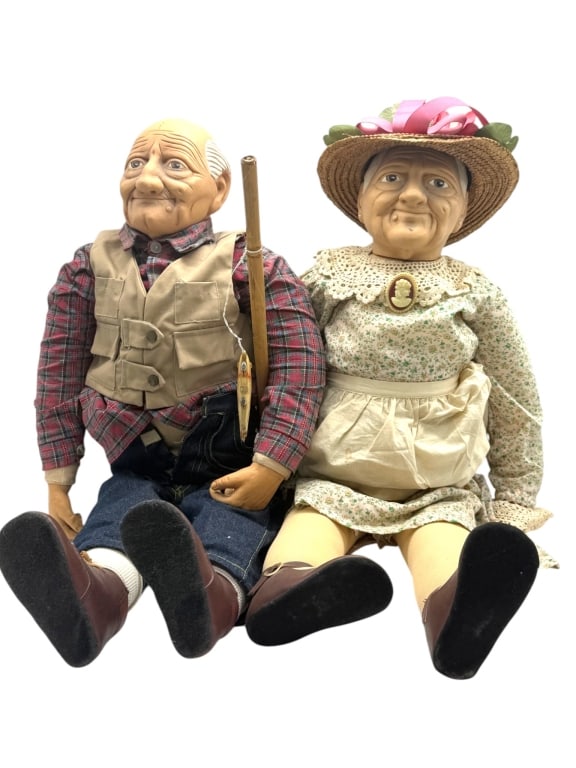 WILLIAM WALLACE GRANDPARENTS DOLL SET 17": A charming pair of grandma and grandpa character dolls by William Wallace in traditional country attire. The gentleman is dressed in a plaid shirt, fishing vest, denim trousers, and boots while holdin
