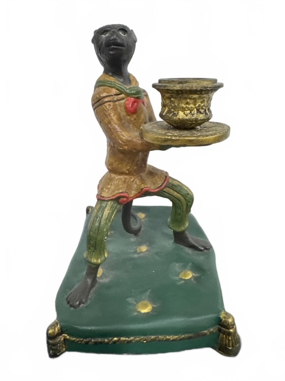 Painted Monkey Figural Candle Holder: Whimsical painted cast figure of a monkey holding a candle cup, dressed in colorful period clothing, standing on a tufted cushion base. Measures approximately 8 inches high. Suitable as a decorative a