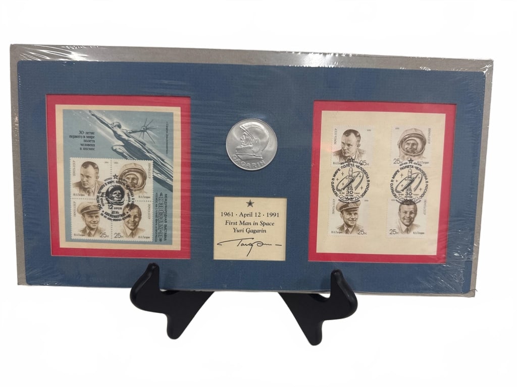 1961 Yuri Gagarin Space Thematic Stamp Set: Framed commemorative display featuring two 1961 Soviet stamps marking Yuri Gagarin's first manned space flight, a central silver medallion, and a facsimile signature card dated April 12, 1961. Attract