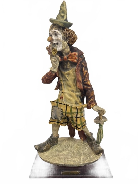 Pucci Clown Figurine on Wood Base: Detailed hand-painted clown figurine by Pucci, standing about 13 inches tall. Features whimsical attire, classic clown makeup, and holds an umbrella. Mounted on a wooden base with engraved artist plaq
