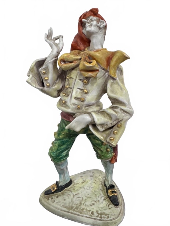 Vintage Porcelain Court Jester Figurine: Hand-painted porcelain figurine depicting a flamboyant court jester with vibrant attire and gold-accented details. Stands approximately 11 inches tall. Well-crafted with expressive pose, ideal for dis