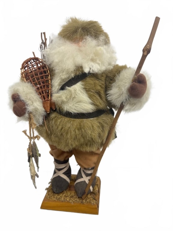 Handcrafted Inuit Fisherman Doll Figurine: This handcrafted figurine depicts an Inuit fisherman dressed in faux fur and fabric winter attire, holding a wooden staff, basket, and fish. The detailed figure stands on a wooden base and measures ap
