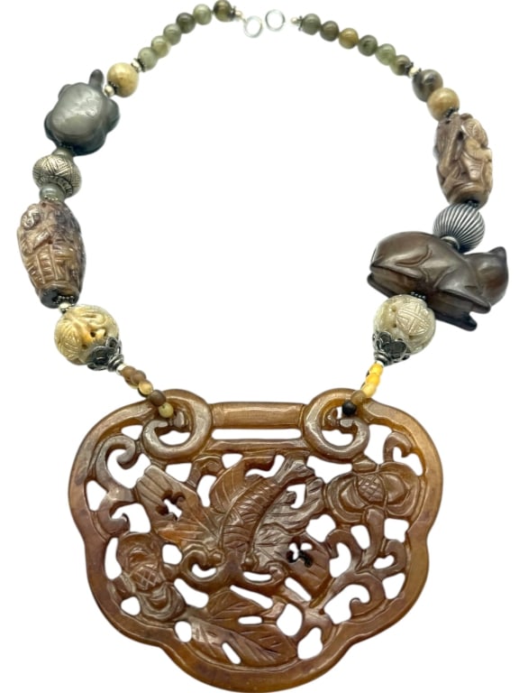 CARVED JADE PENDANT BEAD NECKLACE 10in: Asian-inspired statement necklace featuring a large openwork carved brown jade pendant depicting prawns and water flora in relief. The pendant is suspended from a strand of carved and polished stone b