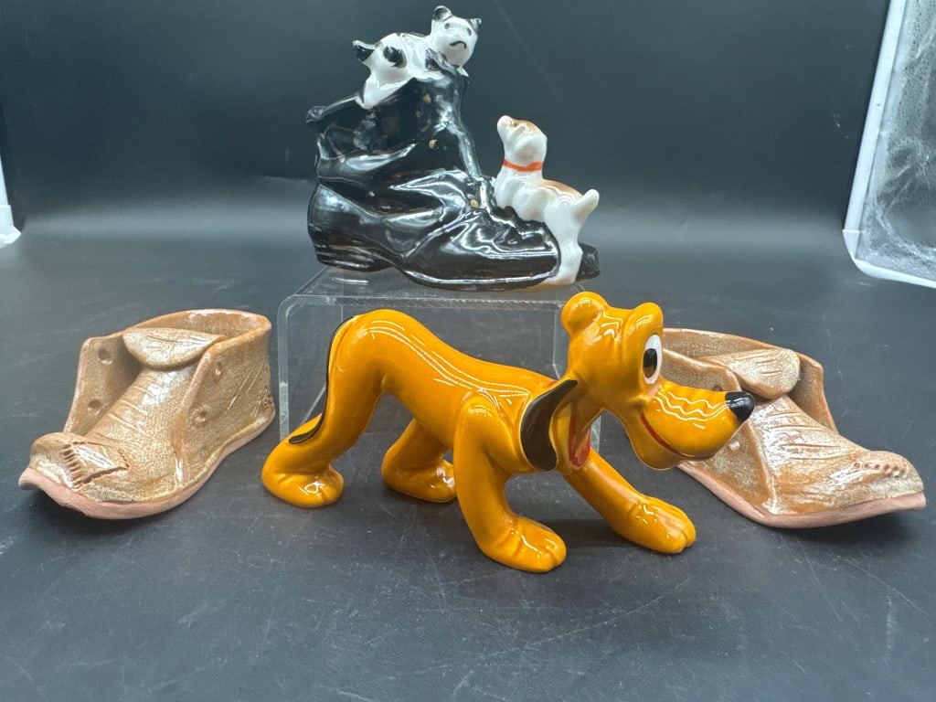 Vintage Ceramic Dog Figurines Set: Three vintage ceramic figurines: one features Disney's Pluto in a bright yellow glaze, another displays two small dogs playing on a black shoe, and the last pair is shaped like brown shoes. Pieces sho
