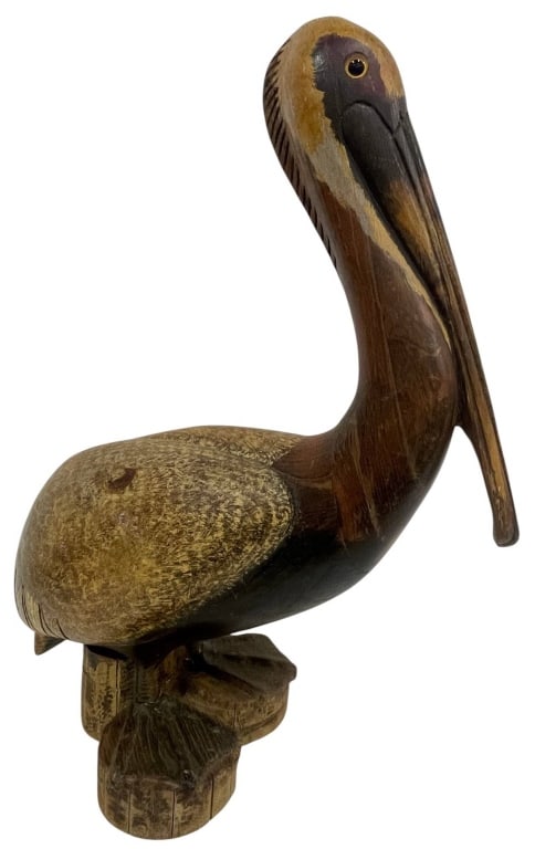 HAND-CARVED WOODEN PELICAN SCULPTURE 25": This hand-carved wooden pelican sculpture is crafted from solid wood and finished with hand-painted naturalistic coloration highlighting the bird's distinctive features. Perched atop a carved dock pil