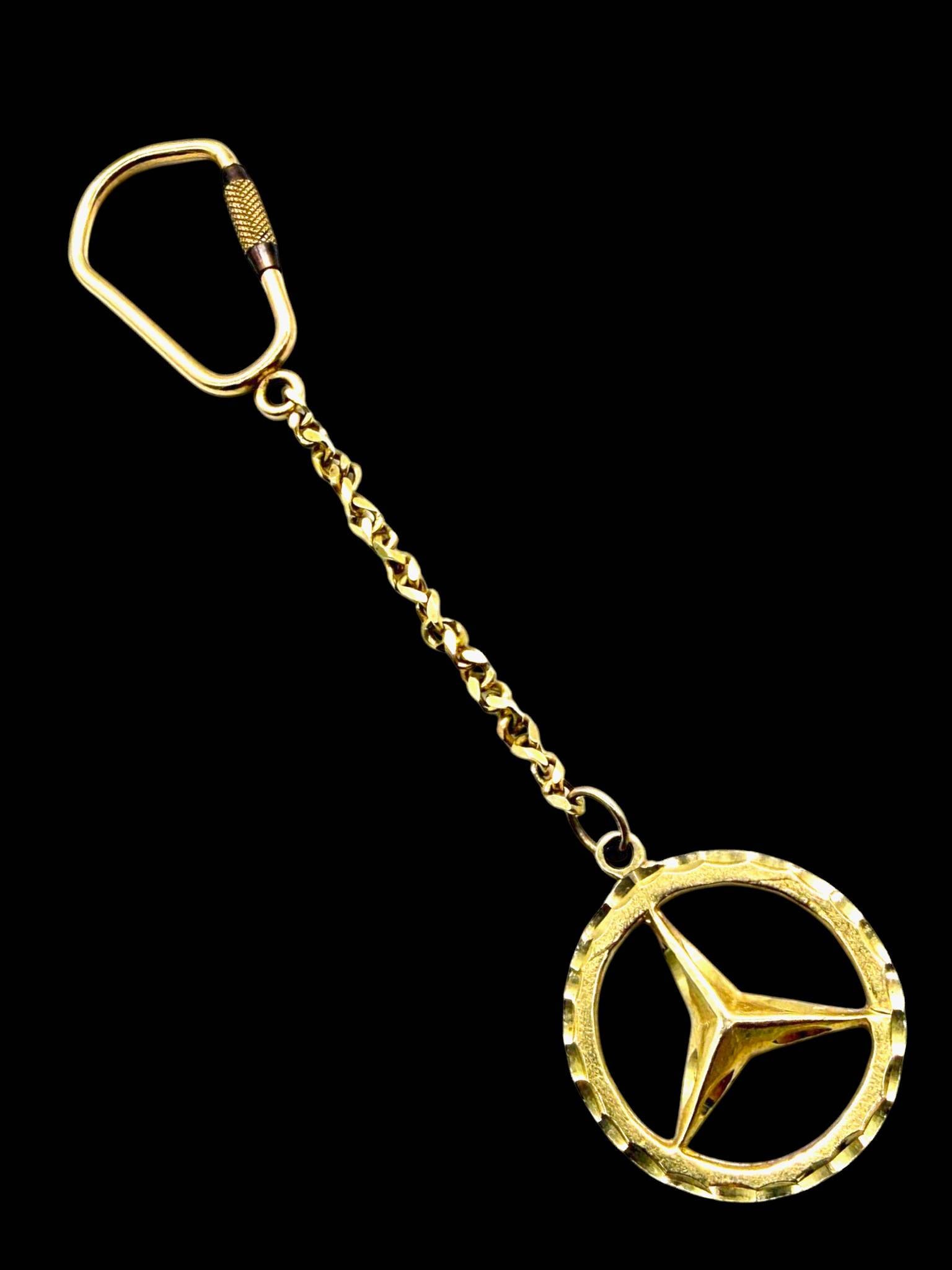 14K GOLD MERCEDES-BENZ KEY RING 4 1/2": This Mercedes-Benz key ring is crafted in solid 14K yellow gold and features the iconic Mercedes three-pointed star emblem suspended from a decorative gold chain and carabiner-style clip. The clip, ch