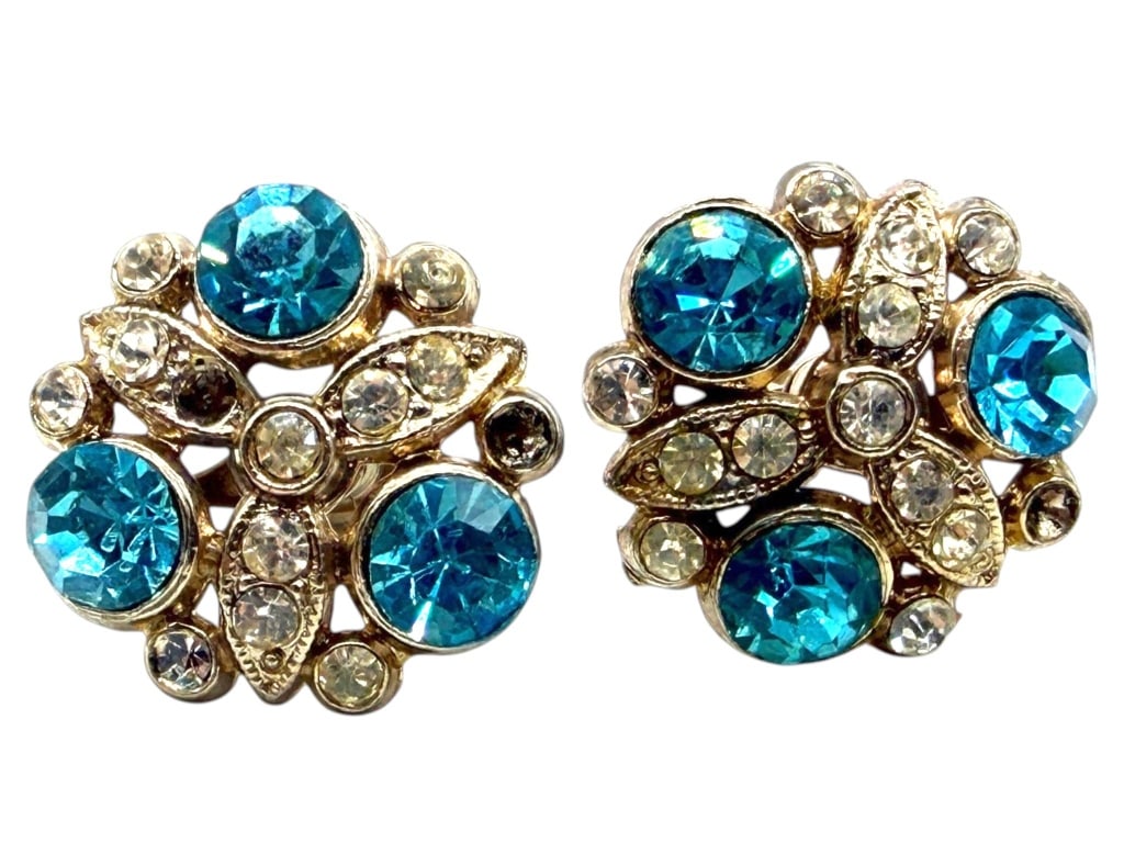 VINTAGE NEMO BLUE RHINESTONE CLIP EARRINGS 1": Pair of vintage signed NEMO clip-on earrings featuring faceted aqua blue rhinestones accented with clear rhinestones in gold-tone metal. Designed in an abstract mid-century modern motif with layered o