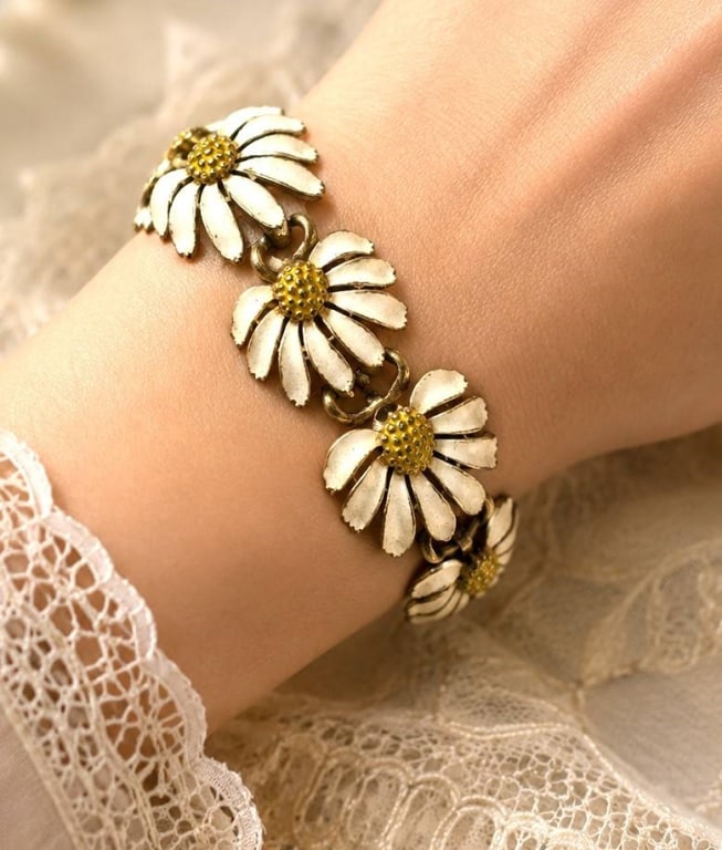 LISNER VINTAGE DAISY LINK BRACELET 7 1/2": Vintage Lisner gold-tone bracelet featuring a charming row of articulated white enamel daisy blossoms with textured yellow centers. Each flower is individually linked to create graceful movement and c