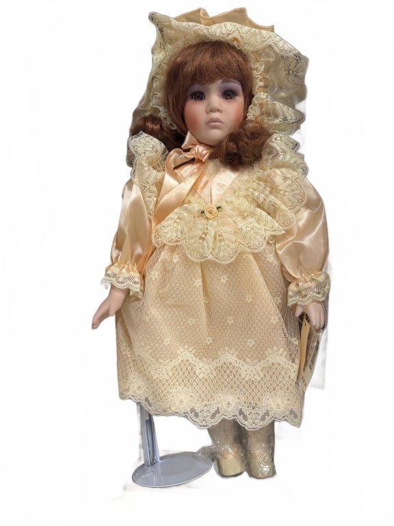 Chatelaine Porcelain Doll with Stand: Chatelaine porcelain doll featuring a lace dress, matching hat, and shoes. Includes original box and clear display stand. The doll has light brown hair and comes with a manufacturer?s tag attached.