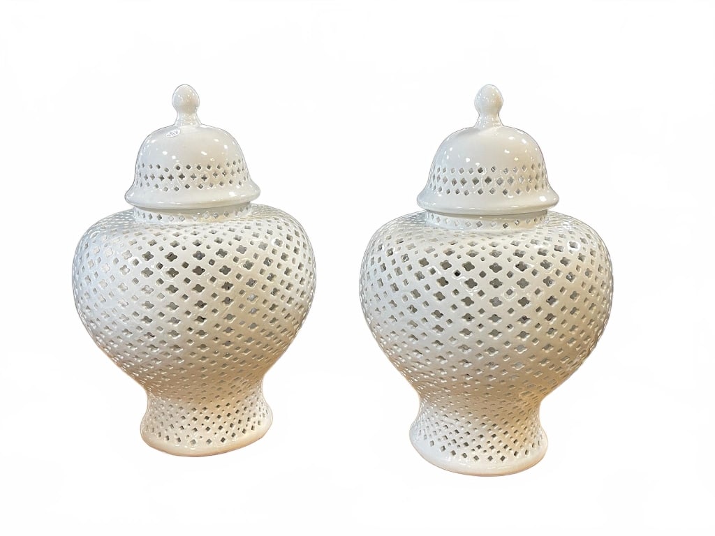 White Pierced Ceramic Ginger Jars: Pair of white ceramic ginger jars with pierced latticework patterns and matching finial lids. Both jars display consistent design and craftsmanship, suitable for decorative purposes. No maker's mark i