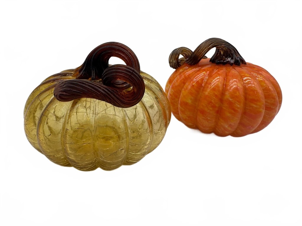 Handblown Glass Pumpkin Figures: Two handblown glass pumpkin figures, one in amber and one in orange with brown glass stems. Each measures approximately 4 inches tall. Both are detailed with ribbed sides and curled stems.