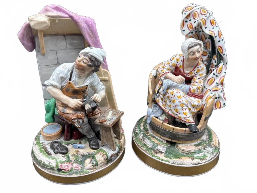 Painted Porcelain Figurines: Hand-painted porcelain figurines depicting a cobbler at work and a seated elderly woman in a chair. Both pieces are detailed with colorful clothing and naturalistic bases. No visible maker marks on
