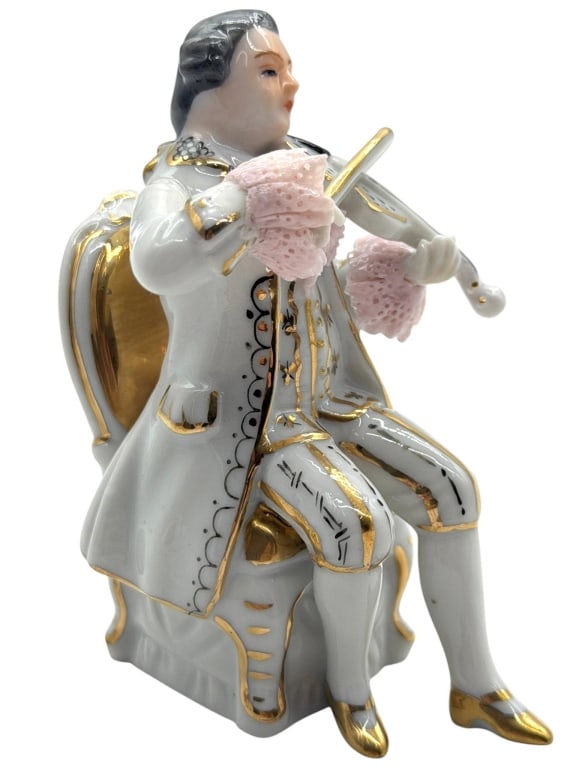 PORCELAIN GENTLEMAN VIOLIN FIGURINE 4": This porcelain figural sculpture depicts an 18th-century gentleman seated in an ornate chair while playing the violin. Executed in a Rococo-inspired style, the figure is finished in a pale gray glaze 