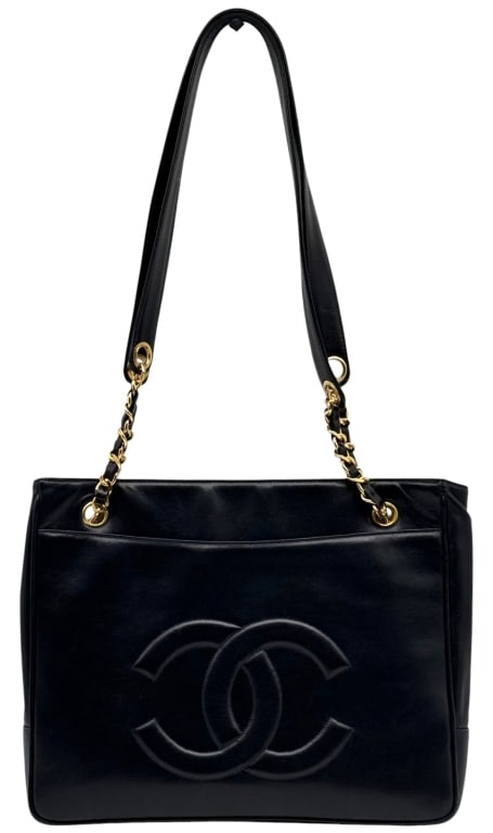 VINTAGE CHANEL CC LOGO LAMBSKIN CHAIN TOTE BAG: Vintage Chanel tote handbag in navy lambskin leather featuring a large stitched CC logo on the front and gold-tone chain-and-leather shoulder straps. The spacious interior includes multiple compartmen