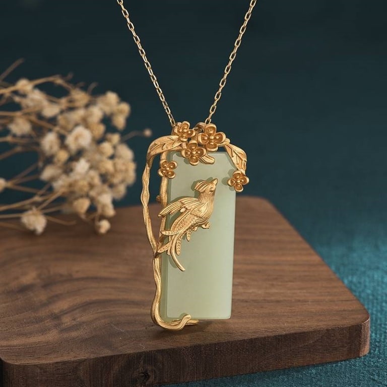 24K GP Gold Jade Pendant Necklace: Rectangular light green jade pendant necklace featuring a 24K gold floral and bird motif surround. Pendant is suspended from a fine 24K GP chain. Includes detailed botanical and avian accents.