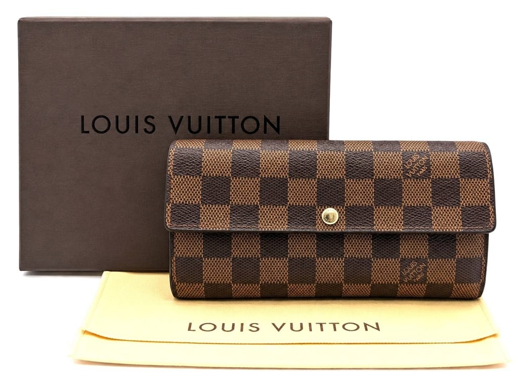 LOUIS VUITTON DAMIER EBENE SARAH WALLET 7": This Louis Vuitton Sarah Wallet is crafted in the iconic Damier Ebene coated canvas with a brown cross-grain leather interior and polished gold-tone hardware. The classic envelope-style design feature