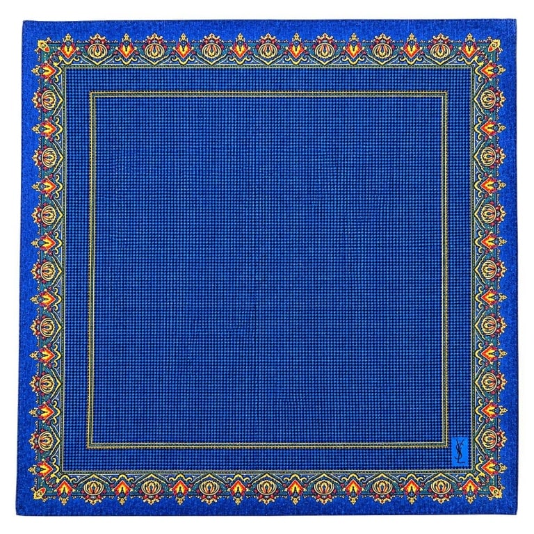 YVES SAINT LAURENT VINTAGE BLUE POCKET SQUARE 16": This vintage Yves Saint Laurent pocket square features a rich sapphire blue micro-check pattern framed by an ornate Persian-inspired border in shades of gold, green, red, and navy. Crafted from a
