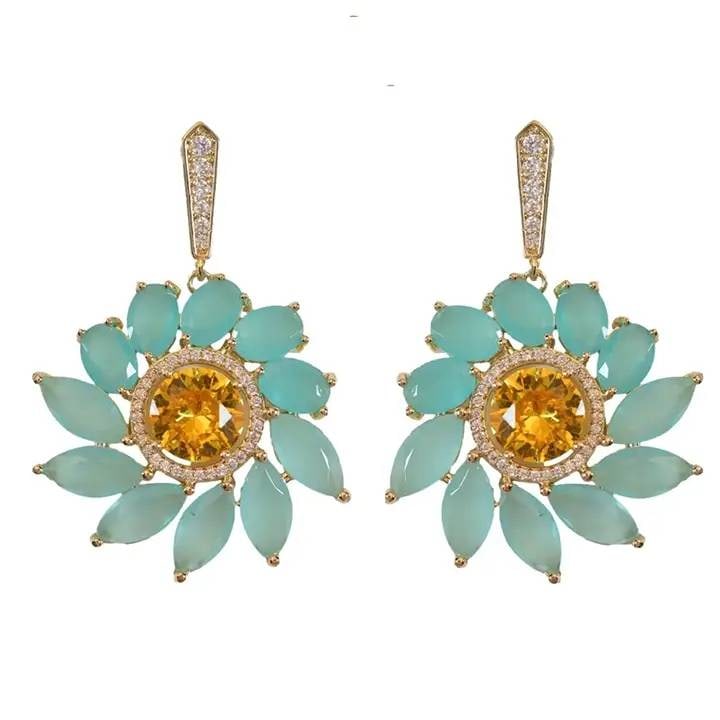 SOLEIL BLOOM CRYSTAL EARRINGS: These 1.75" statement earrings showcase a bold floral design with soft turquoise-toned crystal petals and a glowing golden center, finished with a pav? crystal drop stud. Inspired by sun-drenched Tusc