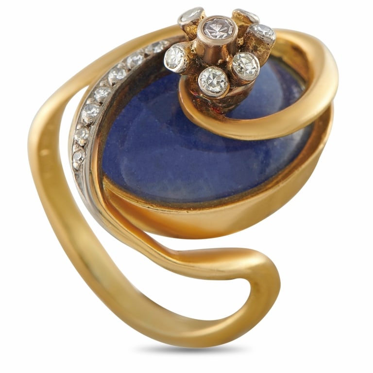 ILIAS LALAOUNIS 18K GOLD 0.11CT DIAMOND RING: A sculptural and boldly designed ring by the legendary Greek jeweler Ilias Lalaounis, crafted in 18K yellow gold and centered on a large oval sodalite cabochon of deep midnight blue. Diamonds totaling