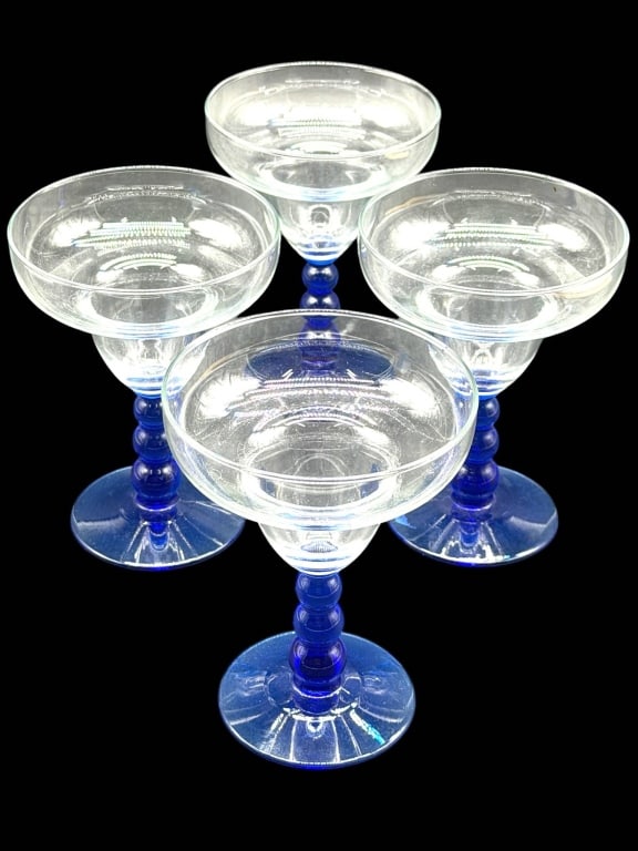 SET OF 4 COBALT MARGARITA GLASSES 6": Vibrant set of four hand-blown style margarita glasses featuring clear bowls paired with striking cobalt blue stems and wide matching blue footed bases. Their classic coupe-style silhouette and bold