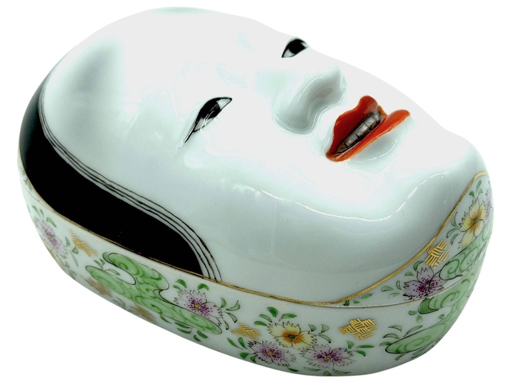 JAPANESE PORCELAIN NOH MASK TRINKET BOX 7": Decorative Japanese porcelain trinket box modeled as a traditional Noh theater mask with a removable lid forming the serene female face. The oval porcelain base is richly decorated with hand-painted f