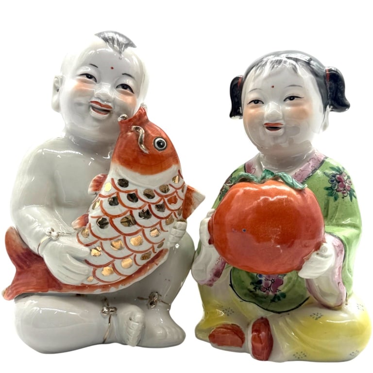 CHINESE PORCELAIN CHILD FIGURINES PAIR 5": Pair of Chinese porcelain child figurines, each hand-painted in colorful famille rose-style enamels with smiling expressions and traditional attire. One child is seated holding a large gilt-accented k