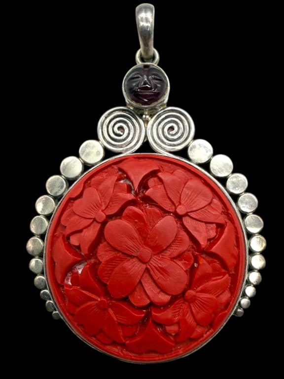 STERLING RED CARVED CINNABAR PENDANT 3": Handcrafted sterling silver pendant featuring an intricately carved circular red cinnabar plaque depicting layered floral blossoms in high relief. The pendant is framed by graduated sterling silver be