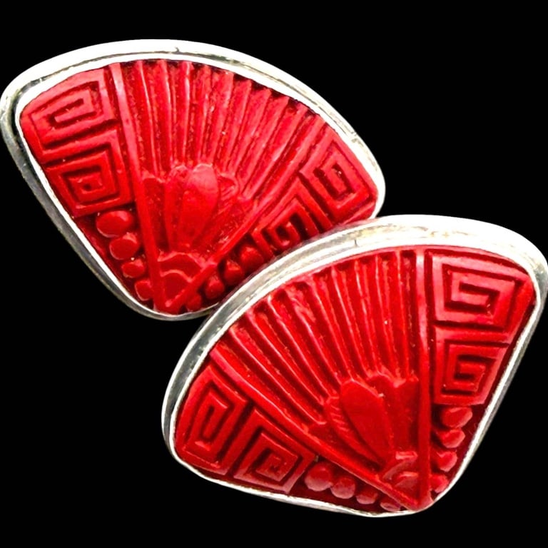 SAJEN STERLING CINNABAR BALINESE CLIP EARRINGS 1": Striking pair of Sajen sterling silver clip-on earrings featuring richly carved red cinnabar panels with bold Art Deco-inspired geometric and floral motifs. The vivid cinnabar carvings are bezel set w