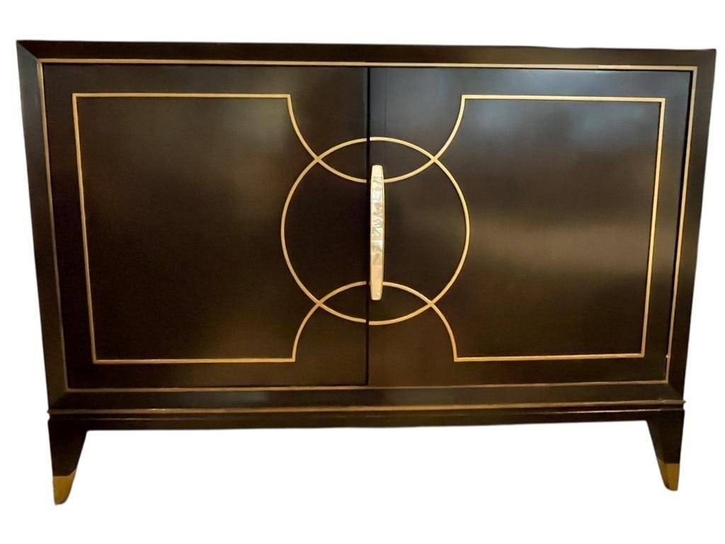 LEXINGTON ART DECO REVIVAL CABINET 50": ished in a high-gloss black or dark espresso lacquer, providing a reflective and elegant canvas for the bold, geometric gold-toned banding that creates an interlocking circle motif across the doors. T