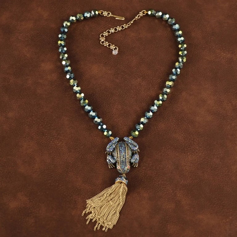VINTAGE FROG 18K GP NECKLACE: This stunning vintage-inspired frog necklace features a vibrant frog-shaped pendant adorned with sparkling blue crystals and bright red eyes. The charming pendant is complemented by a tassel made of