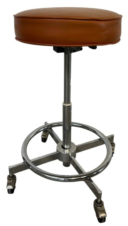 VINTAGE ADJUSTABLE INDUSTRIAL STOOL 27": Vintage adjustable industrial rolling stool featuring a round caramel brown padded vinyl seat atop a chrome-plated steel pedestal with a five-star rolling base and integrated circular footrest. Design