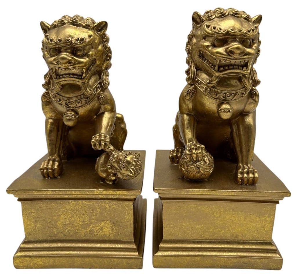 PAIR OF GOLD TONE FOO DOG BOOKENDS 9": Decorative pair of Asian-inspired Foo Dog bookends crafted from composite material with an antiqued gilt finish. Each guardian lion is seated atop a stepped plinth and features traditional symbolic de