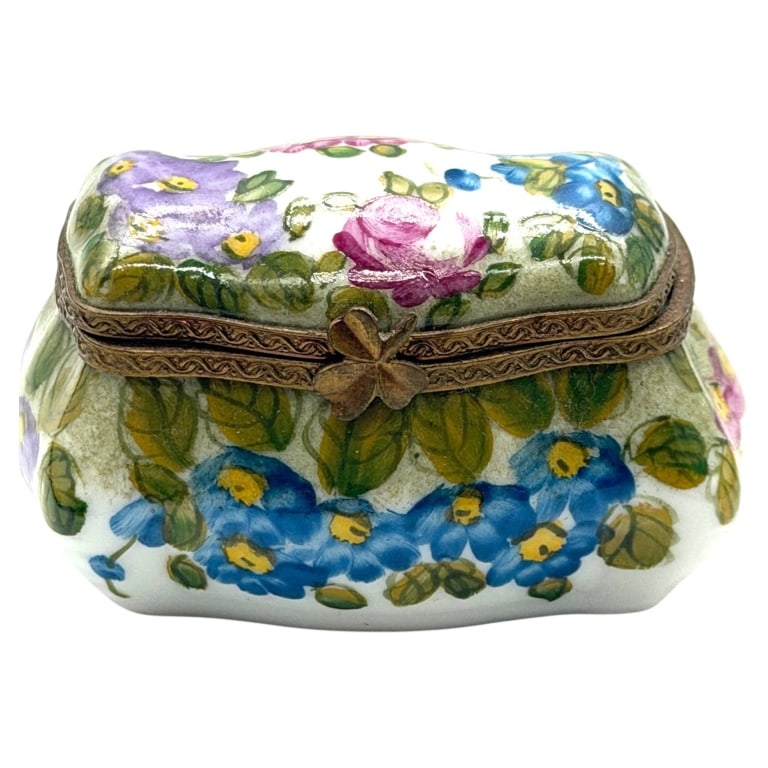 LIMOGES FLORAL TRINKET BOX 1": This charming miniature Limoges hand-painted porcelain trinket box features an all-over floral motif with vibrant blue, pink, and lavender blossoms accented by soft green foliage. The gently scalloped