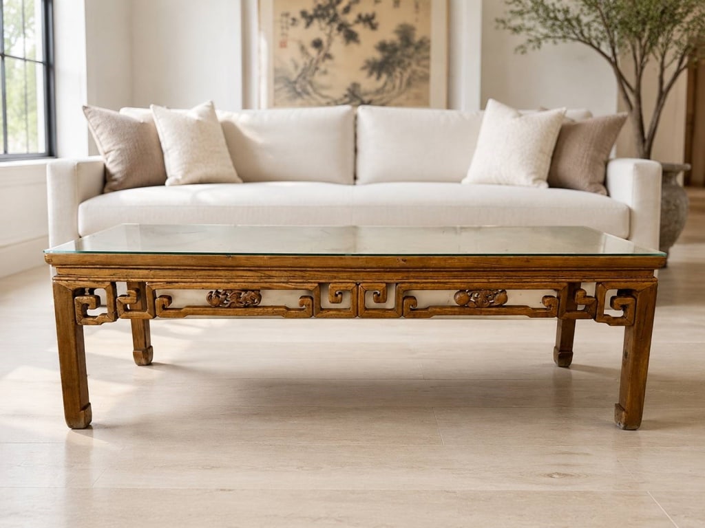 VINTAGE CHINESE CARVED WOOD COCKTAIL TABLE 68": CHINESE CARVED WOOD COCKTAIL TABLE 68" | | Long Chinese-style cocktail table featuring a warm-toned carved wood frame and a substantial rectangular glass top. The openwork apron is decorated with repe