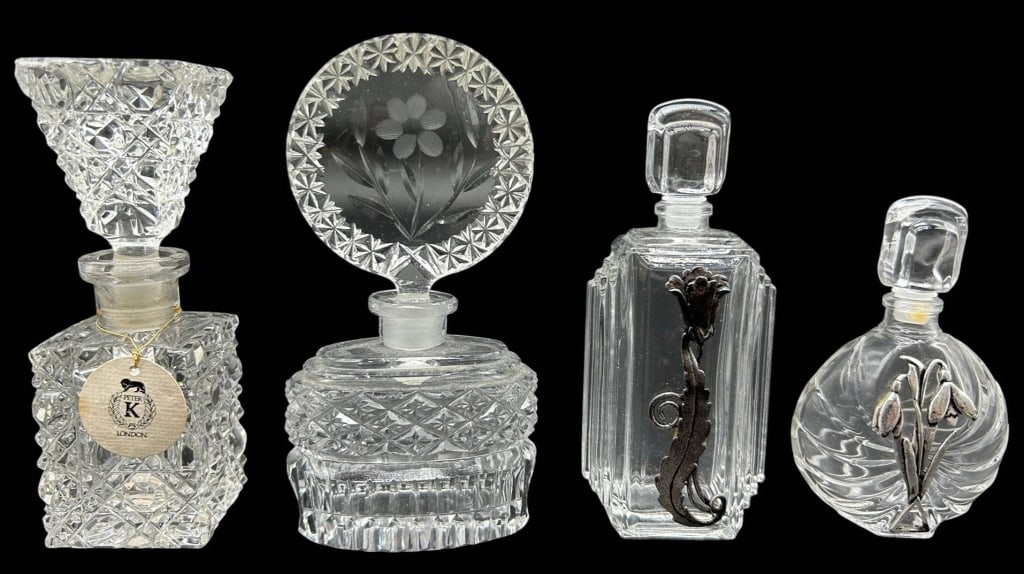 FOUR VINTAGE CRYSTAL PERFUME BOTTLES 5": Collection of four vintage crystal and glass perfume bottles featuring a variety of decorative forms and stopper designs. Includes a square cut crystal bottle with original stopper and Peter K. London