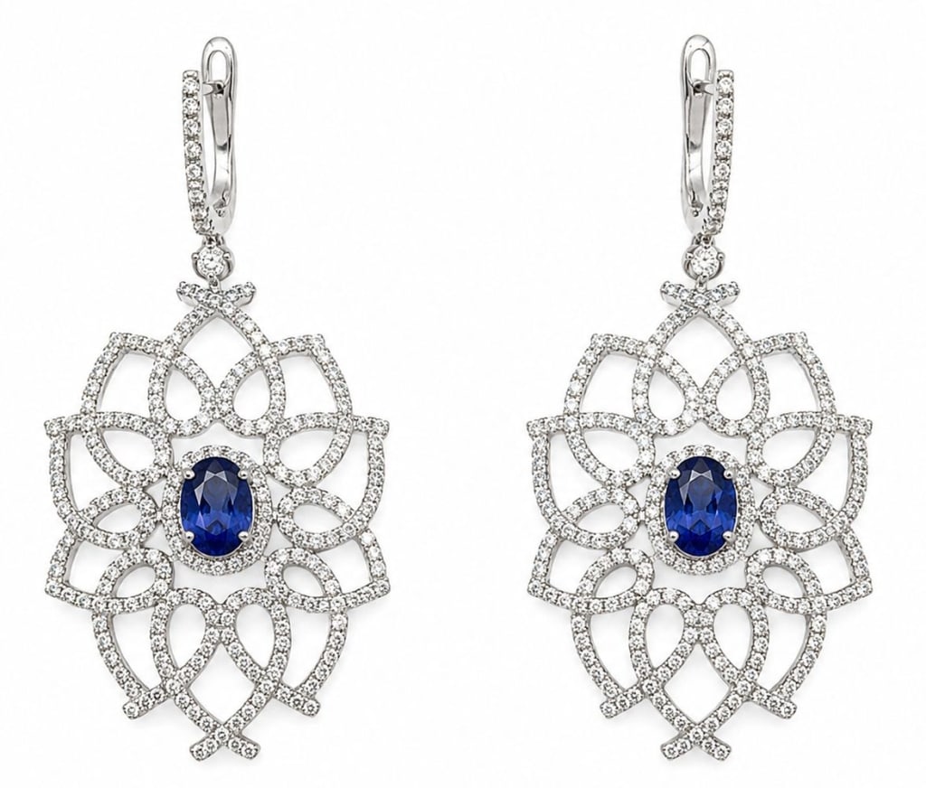 GGA 14K WHITE GOLD TANZANITE DIAMOND EARRINGS: Pair of 14K white gold drop earrings featuring two natural oval-cut tanzanites with a combined weight of approximately 1.60 carats. The openwork floral design is accented by round brilliant-cut diamon