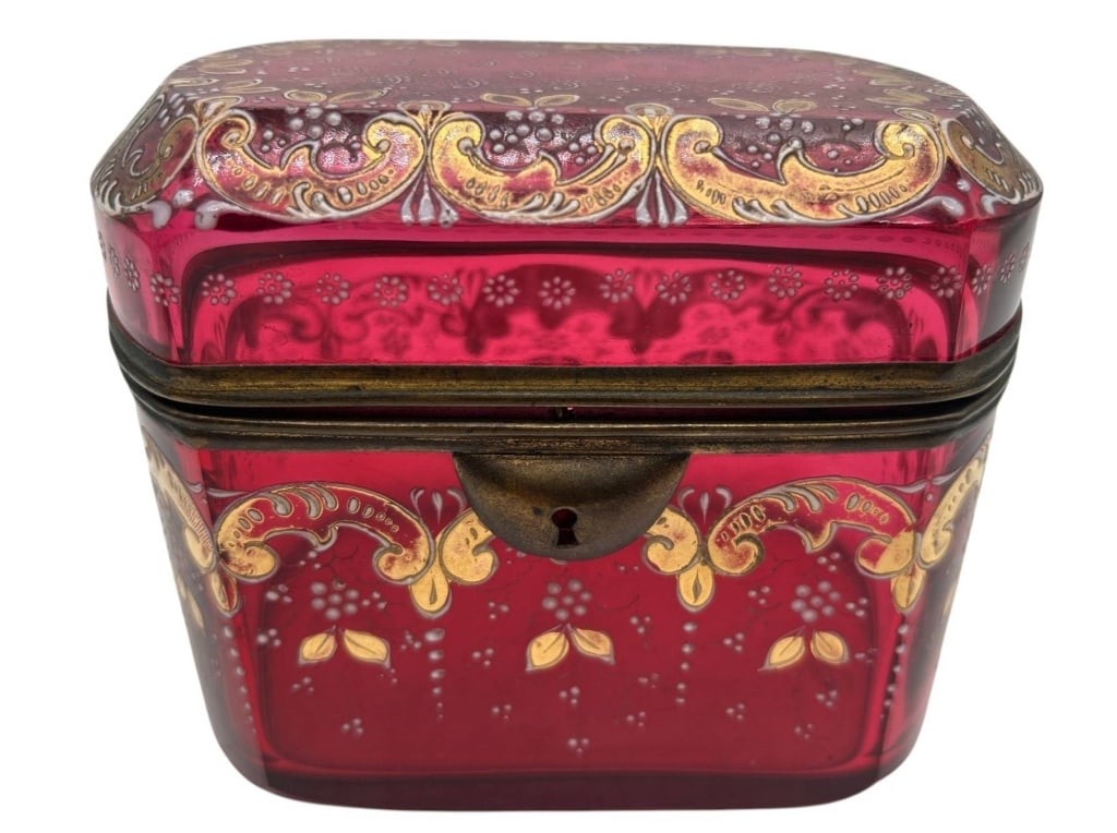 ANTIQUE RUBY GLASS GILT JEWELRY BOX 5": Striking antique ruby red glass dresser or jewelry box featuring a richly decorated gilt scrollwork design with delicate white enamel floral accents. The rectangular form has softly rounded corners, a