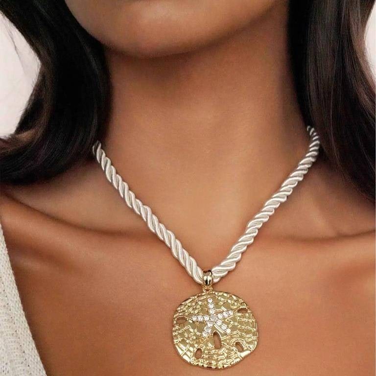 SAND DOLLAR 18K GP PENDANT NECKLACE: This necklace features an 18k GP sand dollar pendant accented with cubic zirconia. The pendant measures 2 inches and hangs on a cream-colored rope chain with an adjustable closure. Total length is 32 