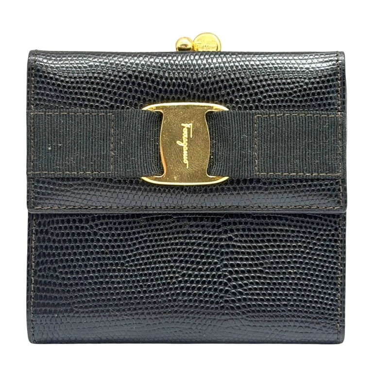 FERRAGAMO VARA LIZARD EMBOSSED WALLET 5": This elegant Salvatore Ferragamo wallet is crafted in black lizard-embossed leather and accented with the iconic Vara grosgrain ribbon and signature gold-tone Vara plaque on the front. The structured 