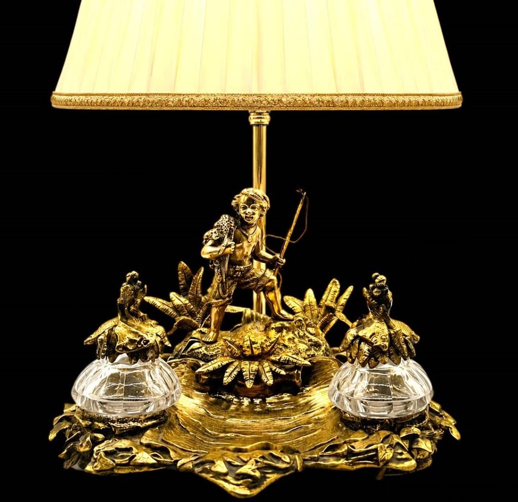 VINTAGE BRASS FIGURAL HUNTER DESK LAMP 11": Elaborate vintage brass-tone figural desk or table lamp featuring a richly detailed tropical hunting scene. The sculptural base centers on a hunter or archer carrying game and holding a bow, surrounde