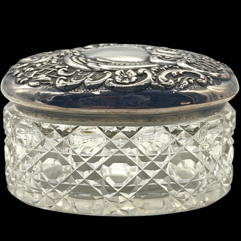 STERLING SILVER & CUT CRYSTAL DRESSER BOX 4": Vintage oval cut crystal dresser, vanity or trinket box with an ornate sterling silver lid. The heavy clear crystal body features deeply cut geometric diamond and faceted motifs that beautifully refle
