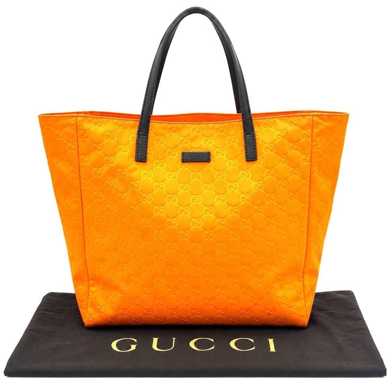 GUCCI TANGERINE GG NYLON TOTE BAG 17": Vibrant Gucci tote crafted in bright tangerine-orange nylon with an allover tonal GG monogram pattern and contrasting black leather shoulder straps. The front is finished with a black leather Gucci