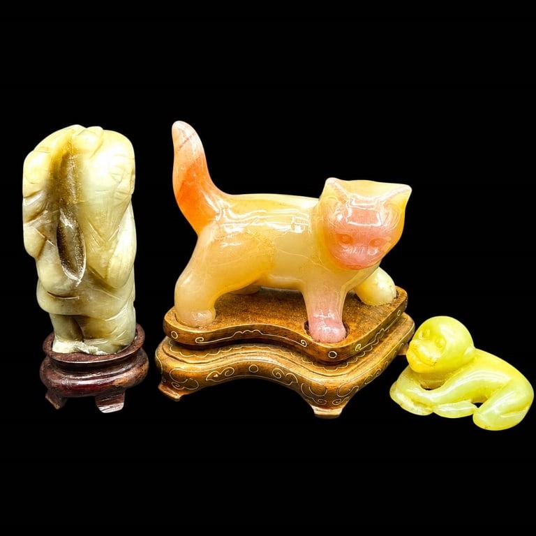 CARVED HARDSTONE JADE FIGURAL LOT 4": Collection of three vintage Asian carved hardstone figures, including a charming standing cat in warm cream, peach and rose tones mounted on an ornate carved wood display stand; a robed standing figur
