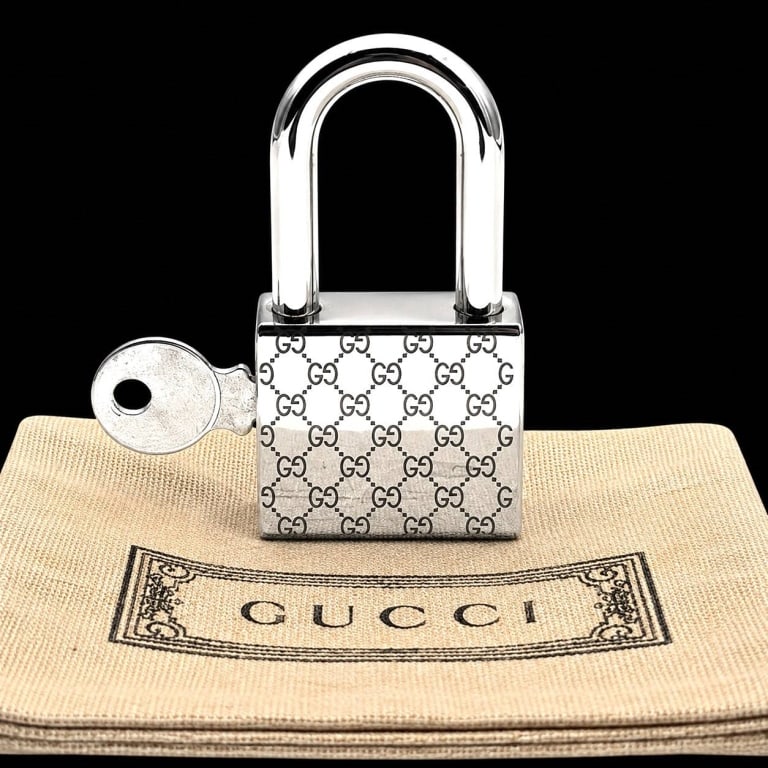 GUCCI GG MONOGRAM PADLOCK WITH KEY 1.5": Vintage Gucci silver-tone metal padlock featuring the iconic repeating GG monogram pattern across the rectangular lock body. Includes coordinating key, also detailed with Gucci-style monogram surface 