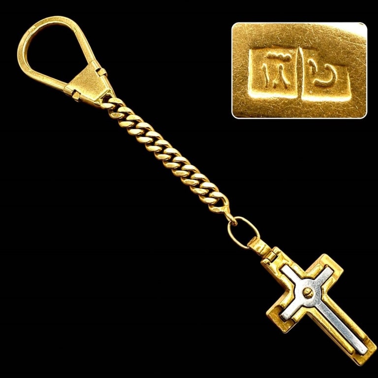 18K GOLD CROSS KEYCHAIN 20.6G: Hallmarked gold keychain featuring a substantial curb-link chain, large spring-style clasp and hinged cross pendant accented with a contrasting silver-tone inlay. The clasp bears two impressed Egyptia