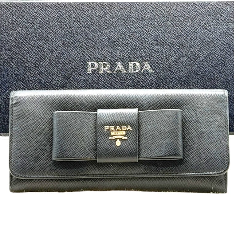 PRADA SAFFIANO BOW WALLET BLACK W ORIGINAL BOX 8": Prada Milano black Saffiano leather continental wallet, an elegant Italian luxury accessory distinguished by its oversized sculptural bow and gold-tone PRADA MILANO DAL 1913 crest hardware. Crafted in