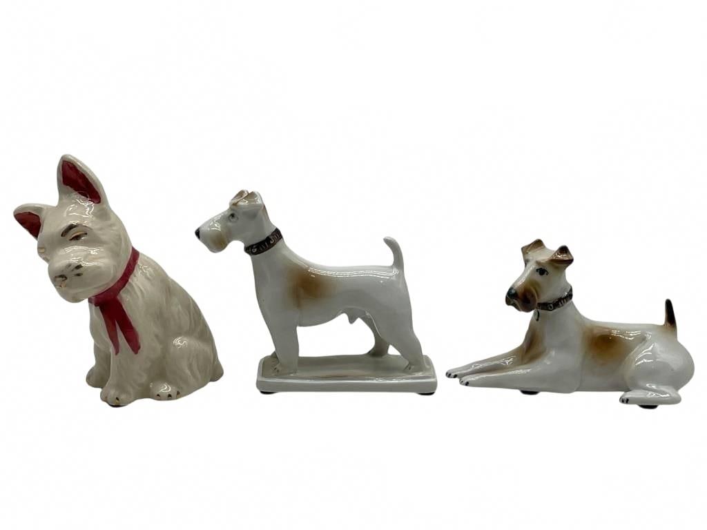 SET OF THREE PORCELAIN TERRIER DOG FIGURINES: SET OF THREE PORCELAIN TERRIER DOG FIGURINES | -Very good pre owned condition | -Approx 3-4" | -A charming set of three porcelain terrier dog figurines, including a seated Scottie with red ribbon and
