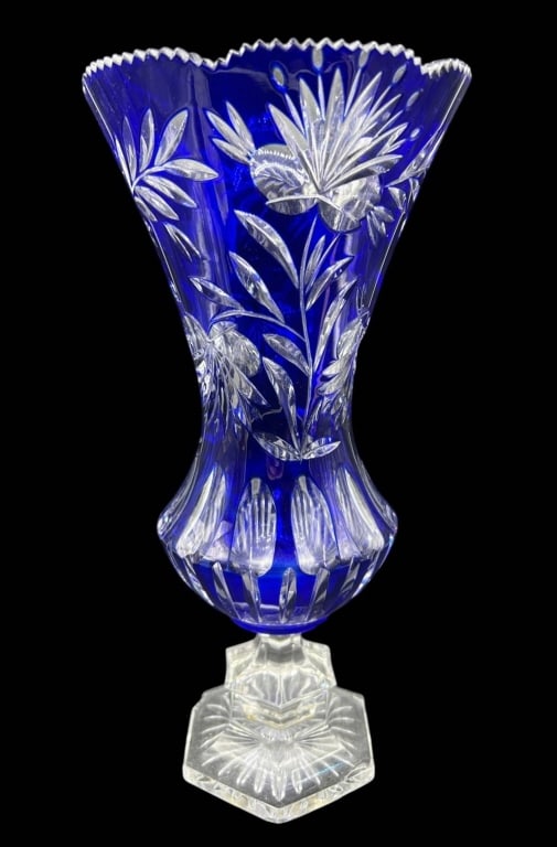 COBALT CUT TO CLEAR CRYSTAL FLORAL VASE 13.5": Tall cobalt blue cut-to-clear crystal vase featuring deeply cut floral and foliate decoration throughout the body. The flared upper section has a dramatic scalloped and sawtooth rim, transitioning to 